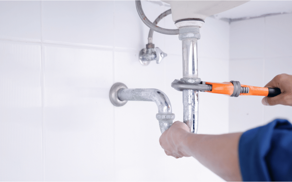 Professional plumber completing bathroom renovation plumbing work with new water lines, fixtures, and drainage connections in a home.