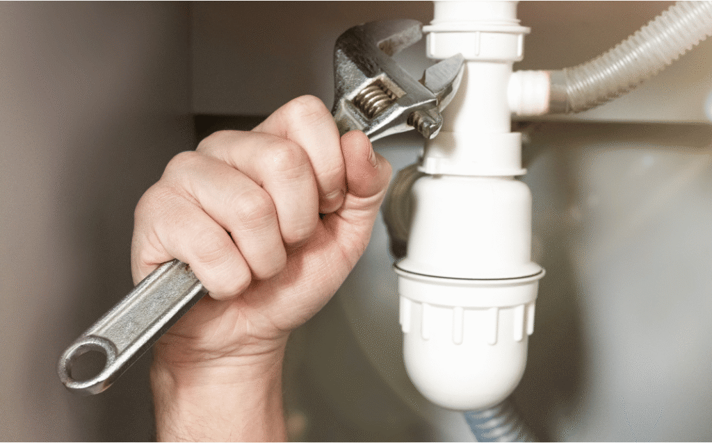 Professional plumber repairing a leaking pipe inside a home